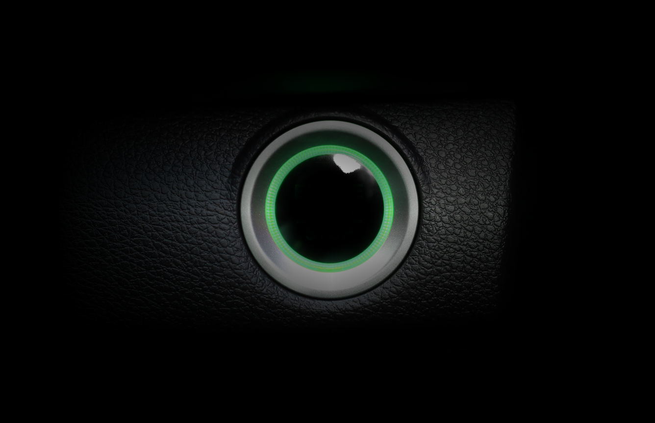A car engine start button in green.